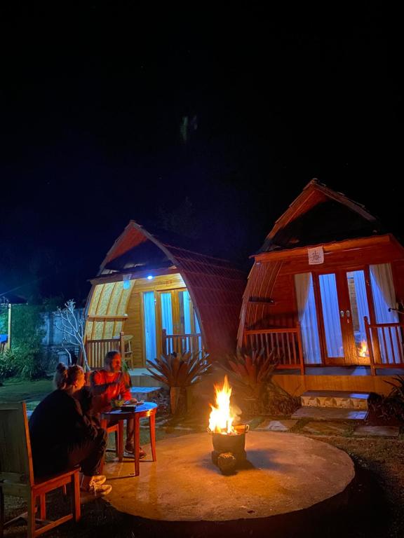 Un groupe de gens assis autour d'un feu la nuit dans l'établissement D'Yoga Bamboo Cabin, à Kintamani