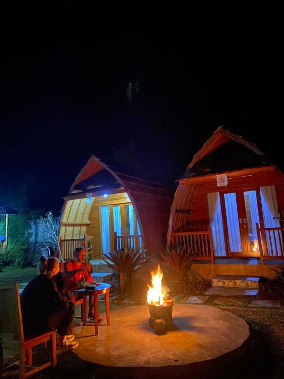 a group of people sitting around a fire at night at D'Yoga Bamboo Cabin in Kintamani