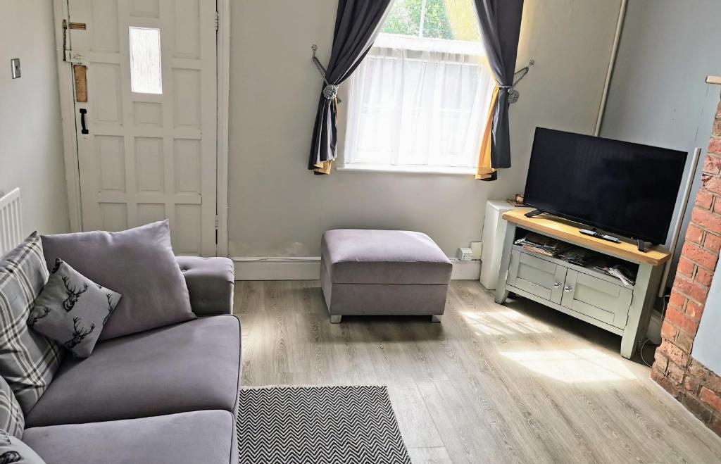 a living room with a couch and a flat screen tv at Wellington Beauty Telford - 4 long term n families sleep comfortably in Wellington