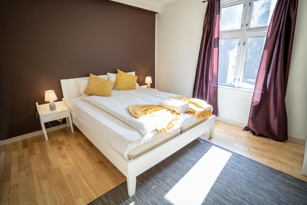 een slaapkamer met een wit bed met gele kussens en een raam bij Central Nicolas Apartment Nr6 Stavanger 4 rooms in Stavanger
