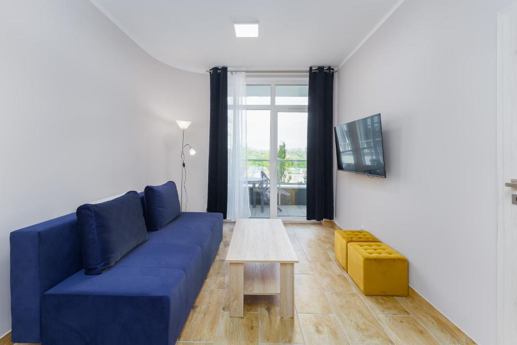Apartament Słoneczny Ku Morzu by HolidaySun في سيانوزيتي: غرفة معيشة مع أريكة زرقاء وطاولة