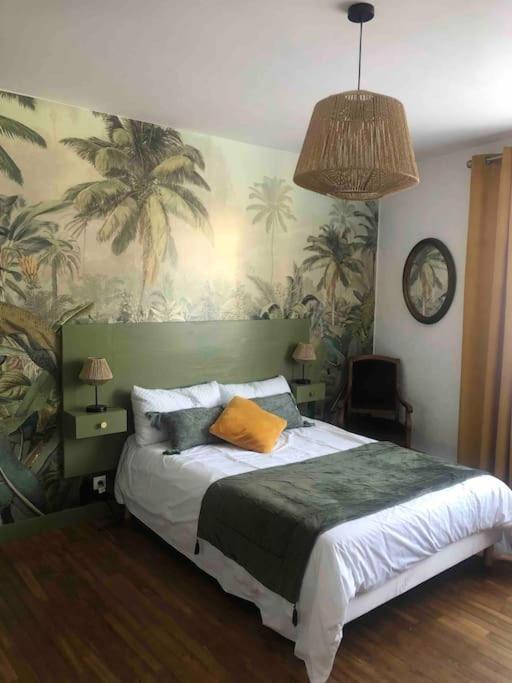 - une chambre avec un grand lit recouvert de palmiers dans l'établissement Une pause entre Mer et Marais, à Niort