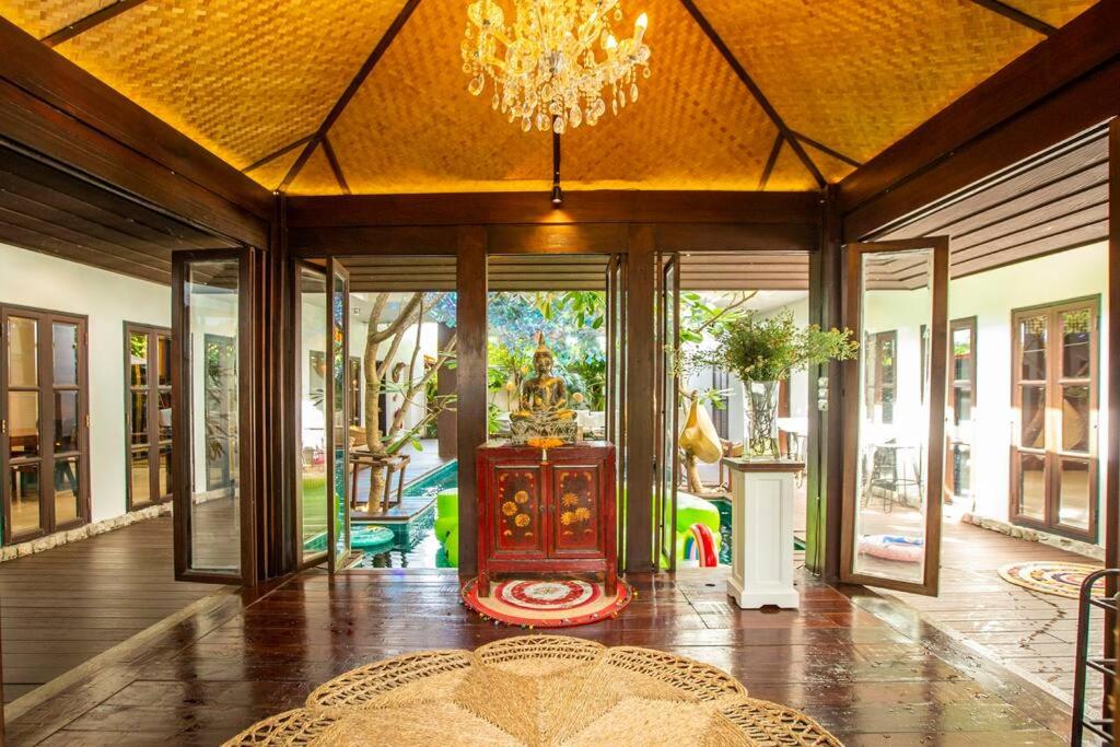 een woonkamer met een kroonluchter en een kamer met glazen deuren bij Unparalleled pool villa in Bangkok