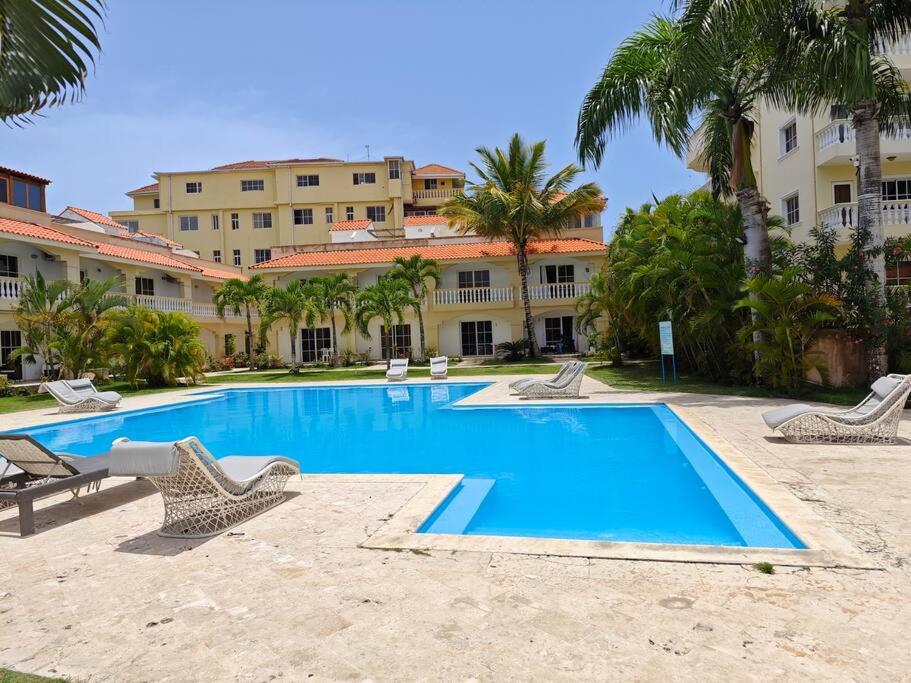 einen Pool mit Liegestühlen und ein Gebäude in der Unterkunft DulceVilla_en la playa in Boca Chica