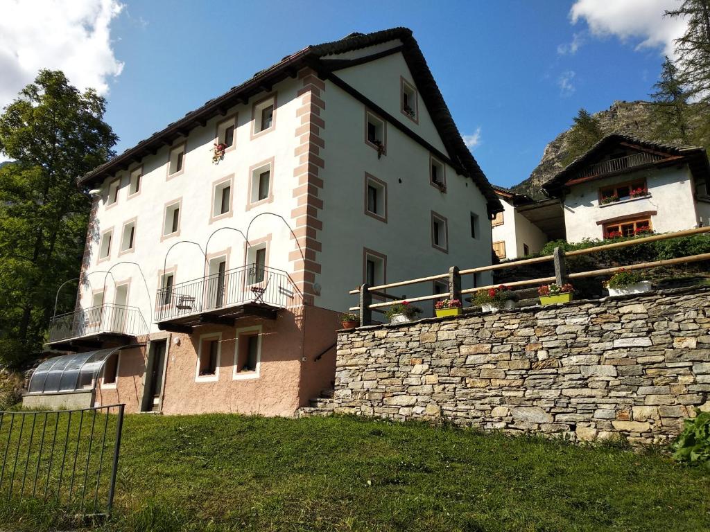 a large white building on a stone wall at Casa Sonnenberg in Bosco Gurin