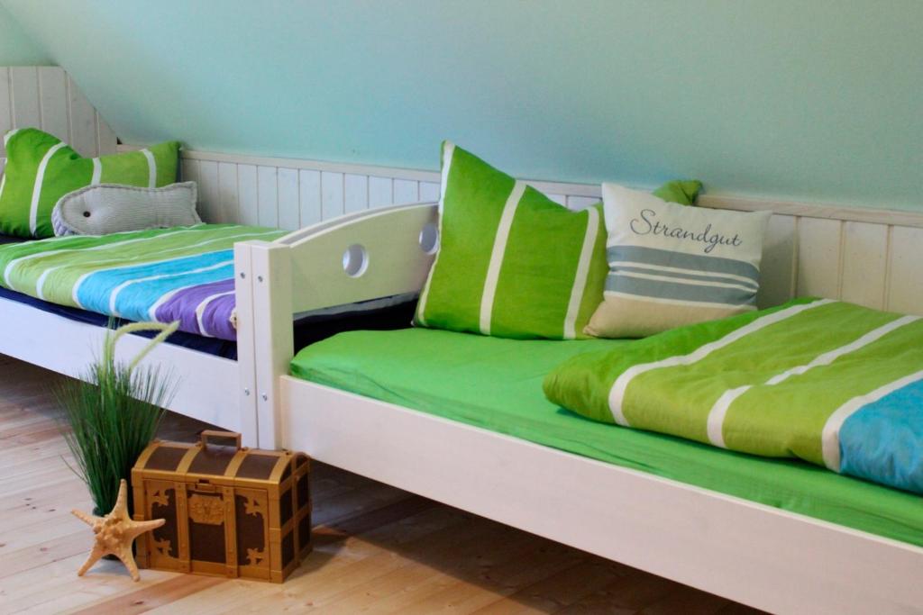two beds in a room with green and white at Huus Strandgut 9140 - Fehmarn in Avendorf auf Fehmarn