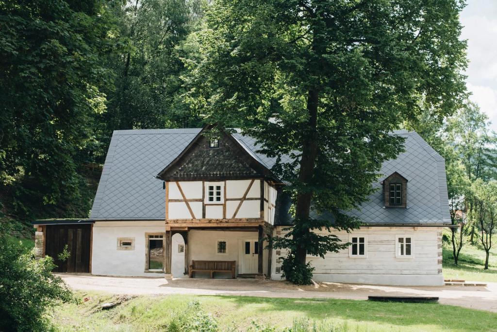 duży biały dom z czarnym dachem w obiekcie V Bezovém Údolí w mieście Kryštofovo Údolí