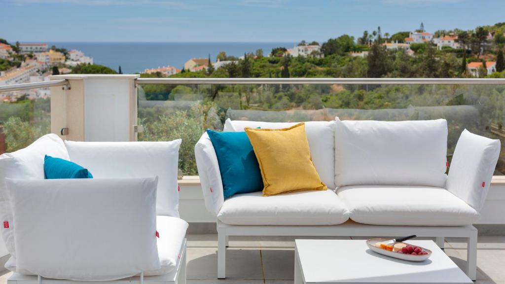 een witte bank en 2 stoelen op een balkon bij Casa Sol 9 by Sevencollection in Carvoeiro