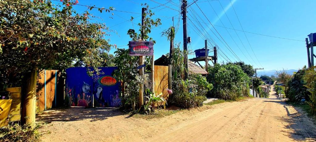 a dirt road with a sign on a fence at Praia do Rosa Hostel in Praia do Rosa