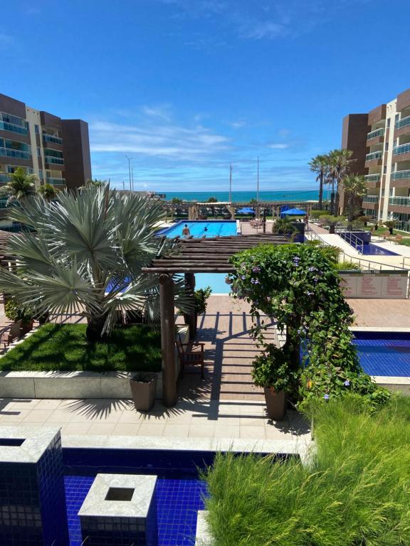 un complexe avec une piscine bordée de palmiers et l'océan dans l'établissement VG Fun Residence Praia do Futuro, à Fortaleza