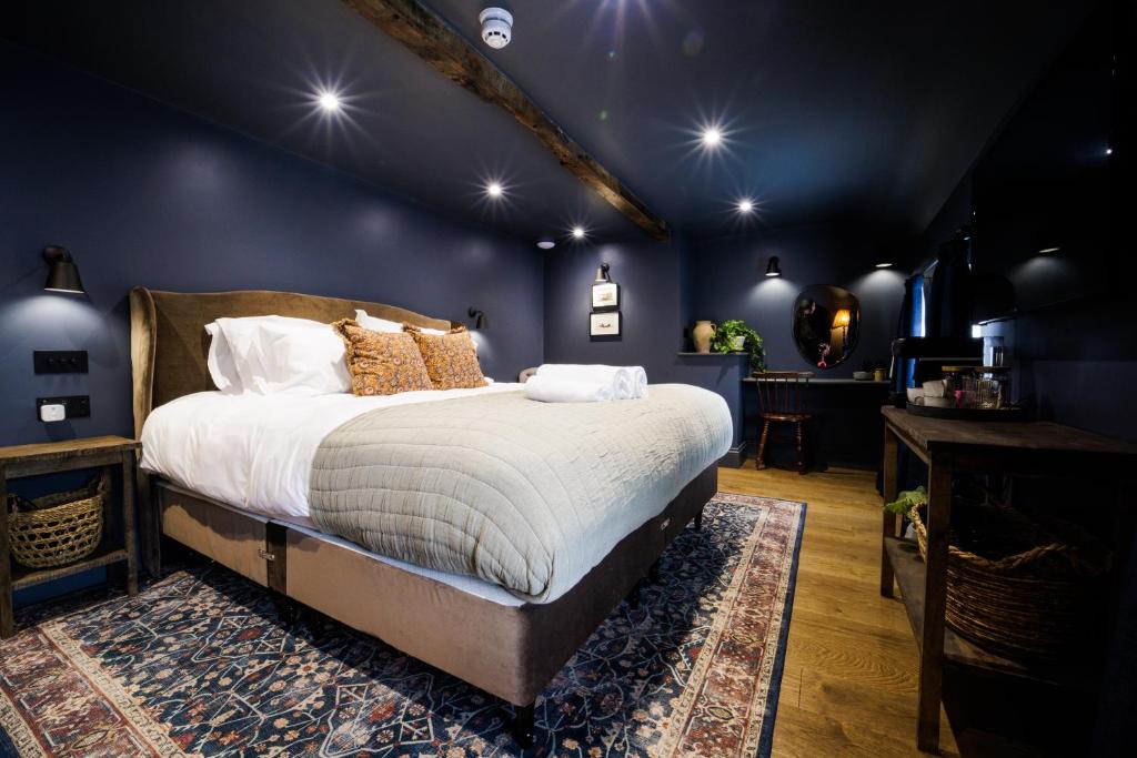 um quarto com uma cama grande num quarto azul em The Silk Rooms, at The Freemasons Inn em Knutsford