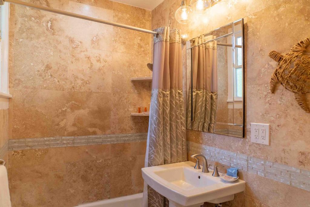 a bathroom with a sink and a mirror and a tub at Southernmost Point Guest House & Garden Bar in Key West