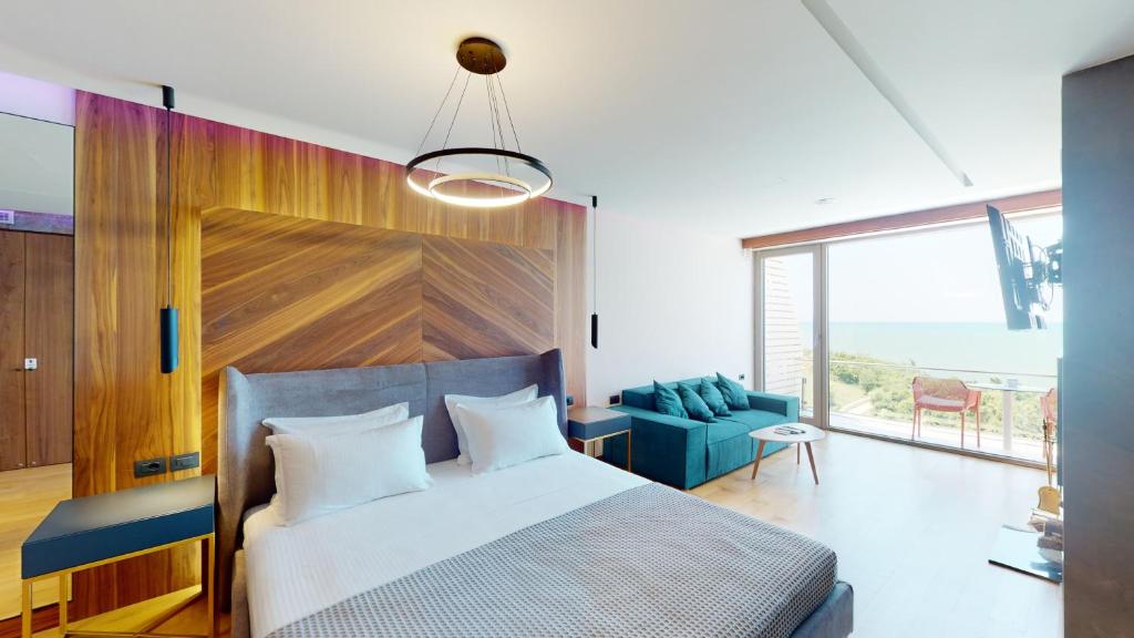 een slaapkamer met een bed en een blauwe bank bij Luxury Apartment Cape of Rodon 2.1 in Shetaj