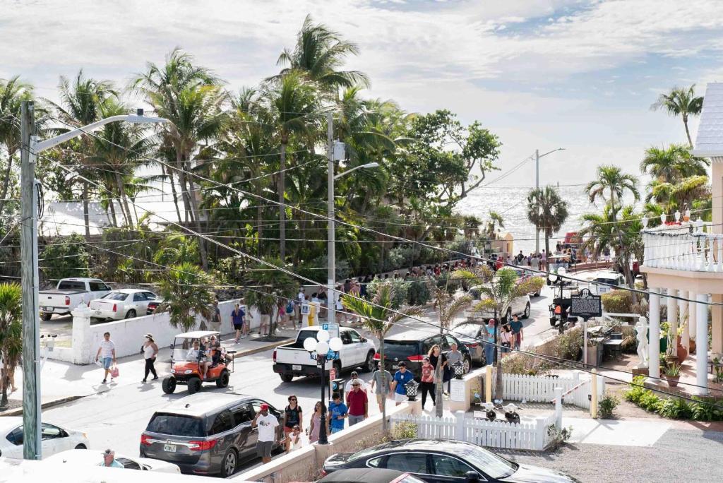 a busy city street with cars and people and palm trees at Southernmost Point Guest House & Garden Bar in Key West