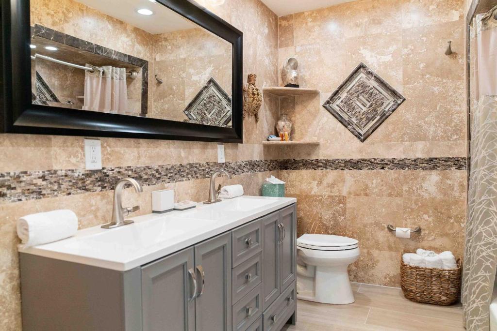 a bathroom with a sink and a toilet and a mirror at Southernmost Point Guest House & Garden Bar in Key West