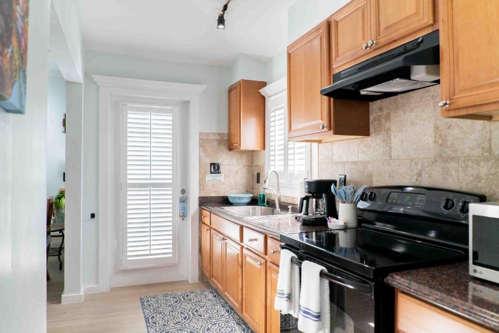 a kitchen with wooden cabinets and a black stove at Southernmost Point Guest House & Garden Bar in Key West