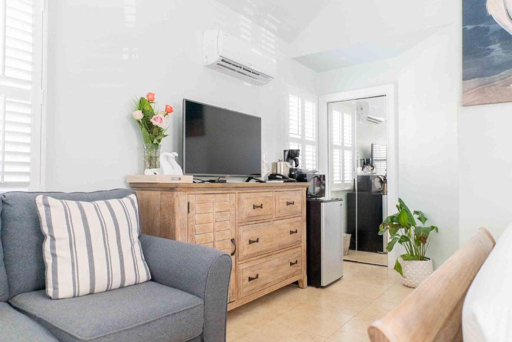 a living room with a television on a wooden dresser at Southernmost Point Guest House & Garden Bar in Key West