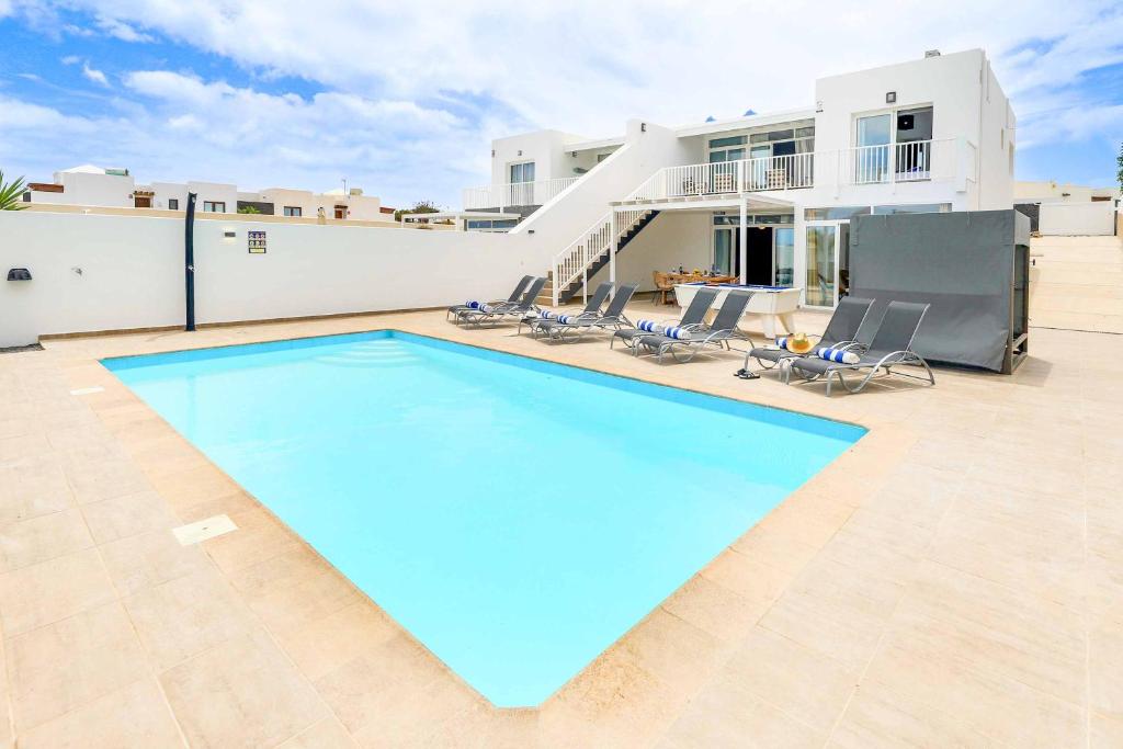 een groot zwembad met stoelen en een huis bij Villa Bella in Playa Blanca