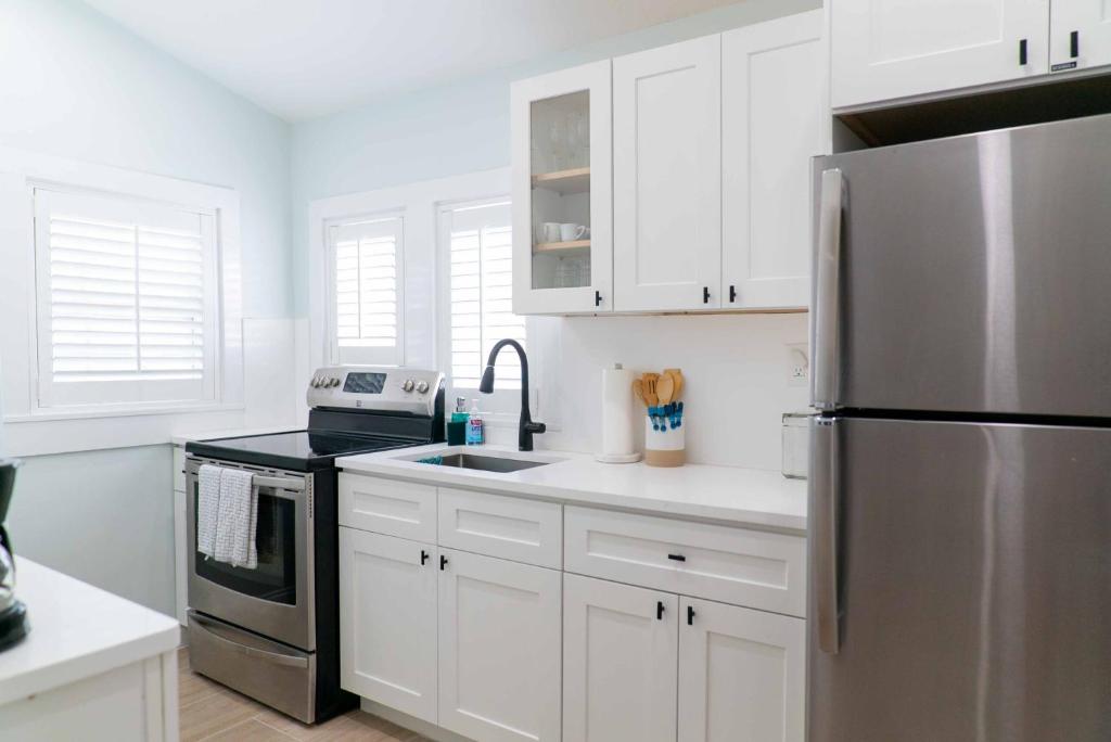a kitchen with white cabinets and a stainless steel refrigerator at Southernmost Point Guest House & Garden Bar in Key West