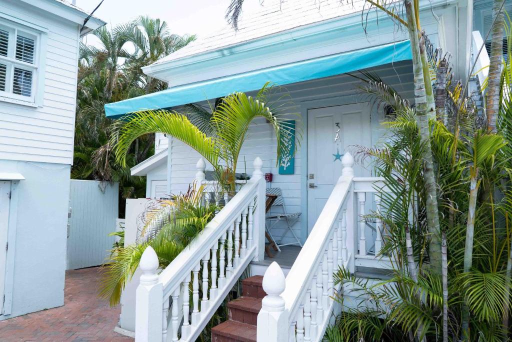 a white house with a white staircase and a blue door at Southernmost Point Guest House & Garden Bar in Key West