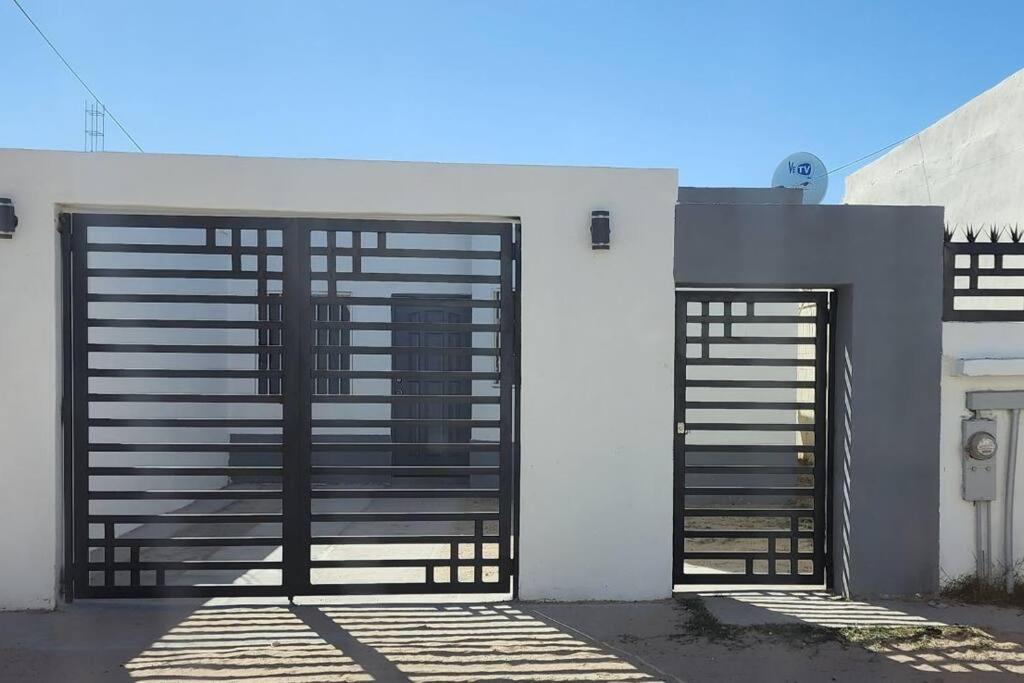 two garage doors on a white building with a gate at Casa Alelies in Puerto Peñasco
