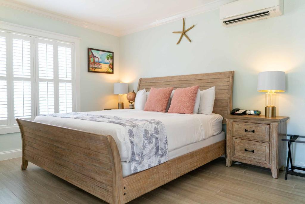 a bedroom with a large bed with white sheets and pink pillows at Southernmost Point Guest House & Garden Bar in Key West