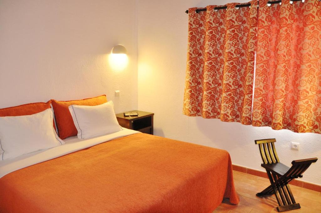 a bedroom with a bed and a window and a chair at Pedras D'el Rei in Tavira