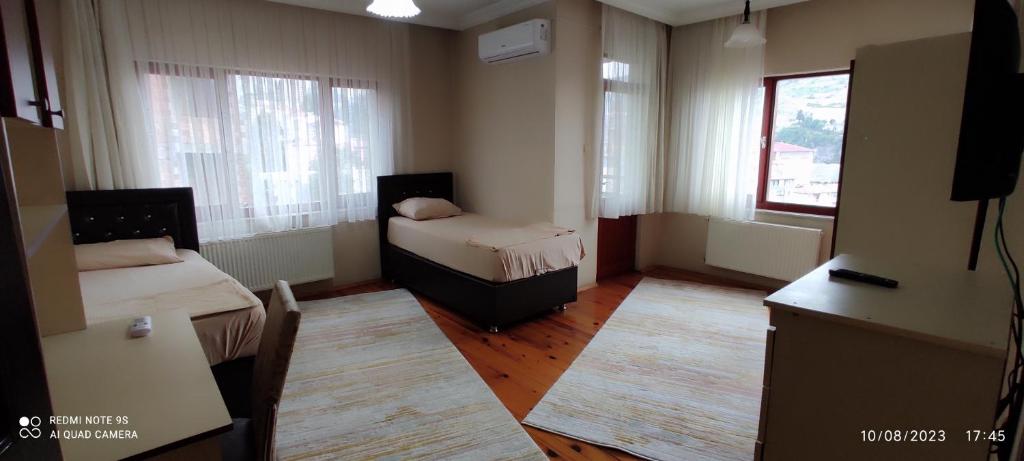 ein kleines Zimmer mit 2 Betten, einem Tisch und einem Fenster in der Unterkunft Kule Apart in Trabzon