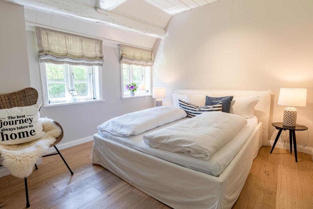 1 dormitorio blanco con 1 cama y 1 silla en Blä Wening, en Borgsum