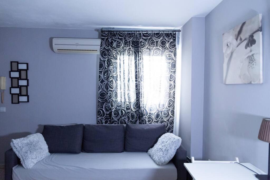 ein Wohnzimmer mit einer Couch vor einem Fenster in der Unterkunft Pasquín in Cádiz