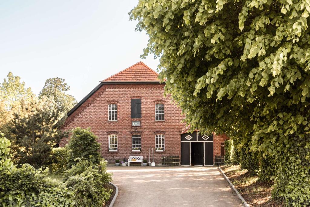 a large red brick building with a driveway at Hofgut Mollberg in Wiefelstede