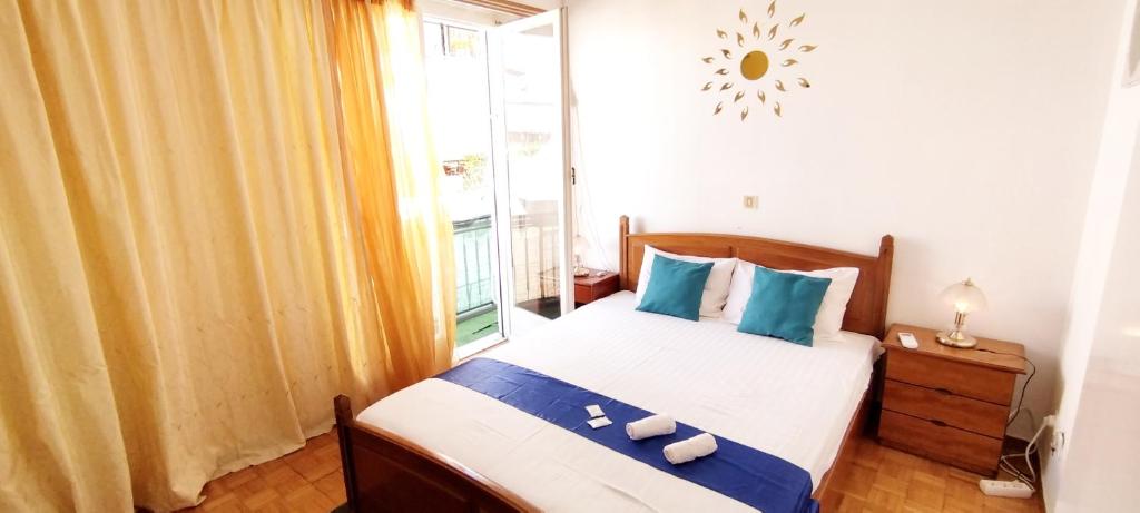 sypialnia z łóżkiem z niebieskimi poduszkami i oknem w obiekcie Cozy room in quiet neighbourhood w Atenach