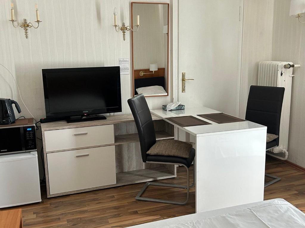 a room with a desk with a television and a desk with chairs at West End Apartments in Frankfurt/Main
