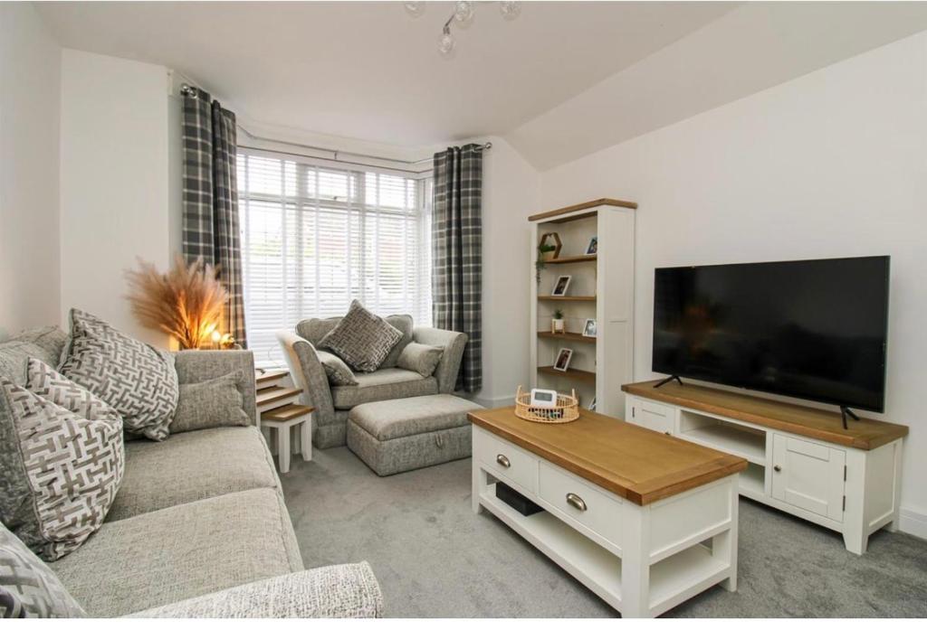 ein Wohnzimmer mit einem Sofa und einem TV in der Unterkunft Home from home in Bexhill