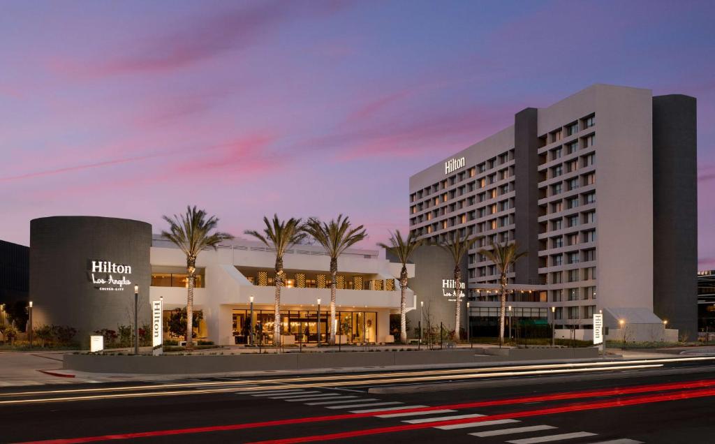 洛杉矶Hilton Los Angeles-Culver City, CA的街道前有棕榈树的建筑