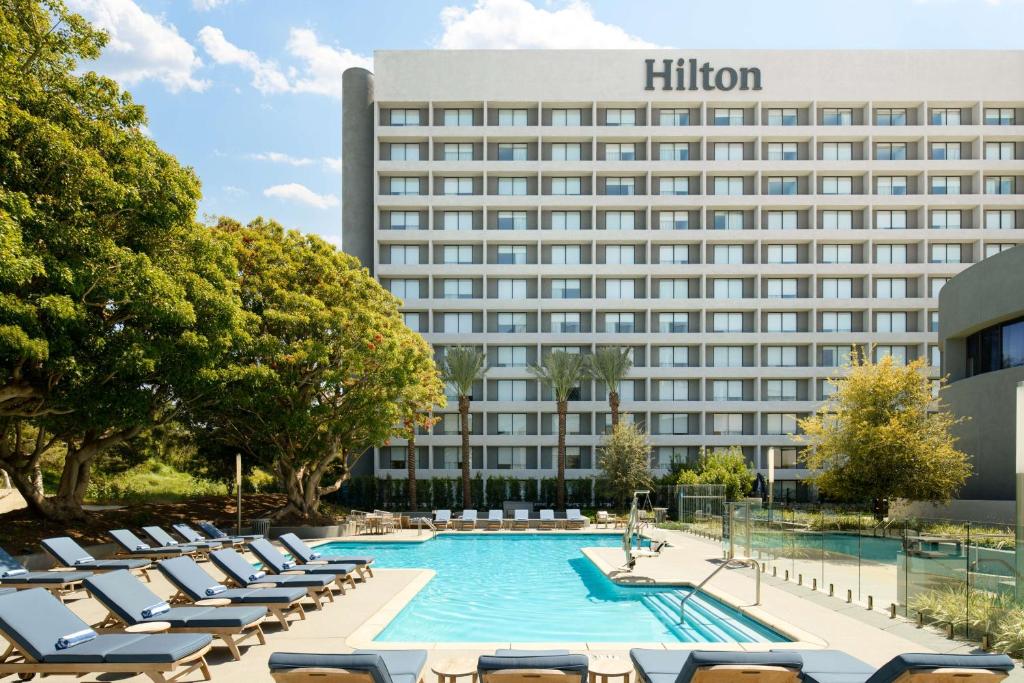 una imagen del hotel Hilton con tumbonas y una piscina en Hilton Los Angeles-Culver City, CA en Los Ángeles