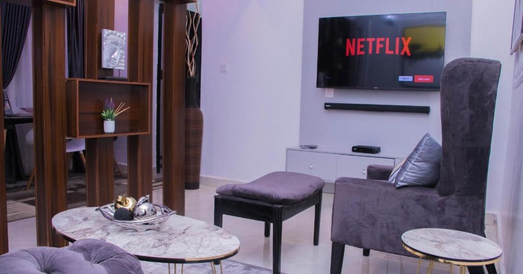 uma sala de estar com uma televisão e uma mesa e cadeiras em JEFA Deluxe Suites em Lagos