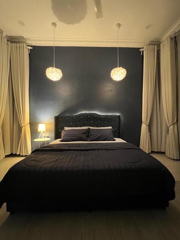 a bedroom with a black bed with two lights at Majestic Homestay - Pasir Puteh in Pasir Puteh