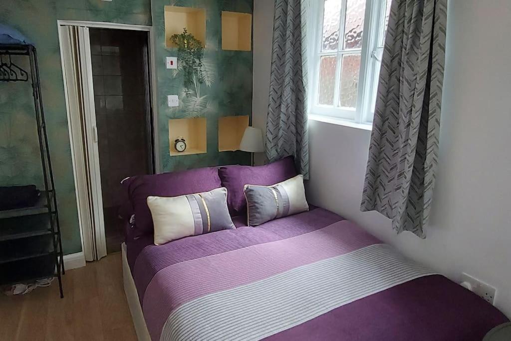 een paars bed in een kamer met een raam bij Quiet and cozy studio in Hendon