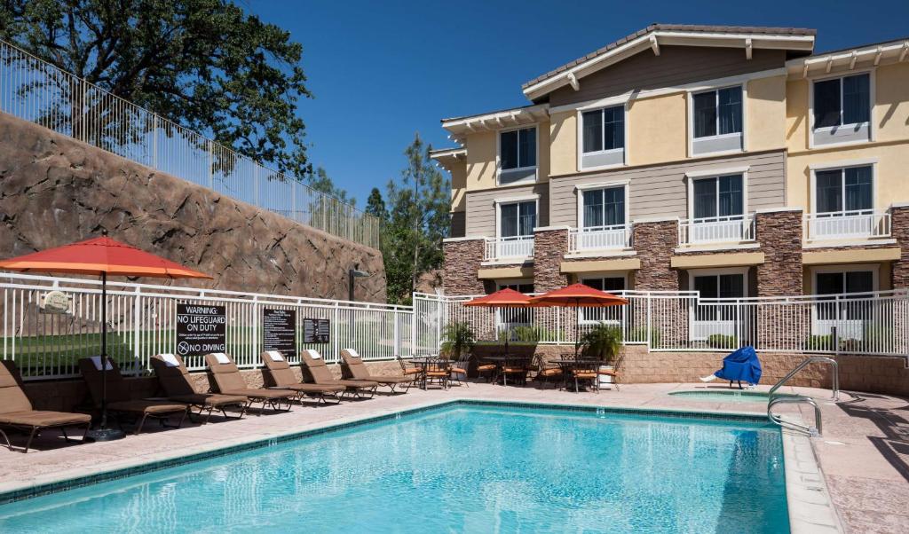 einen Pool in einem Hotel mit Stühlen und Sonnenschirmen in der Unterkunft Homewood Suites by Hilton Agoura Hills in Agoura Hills