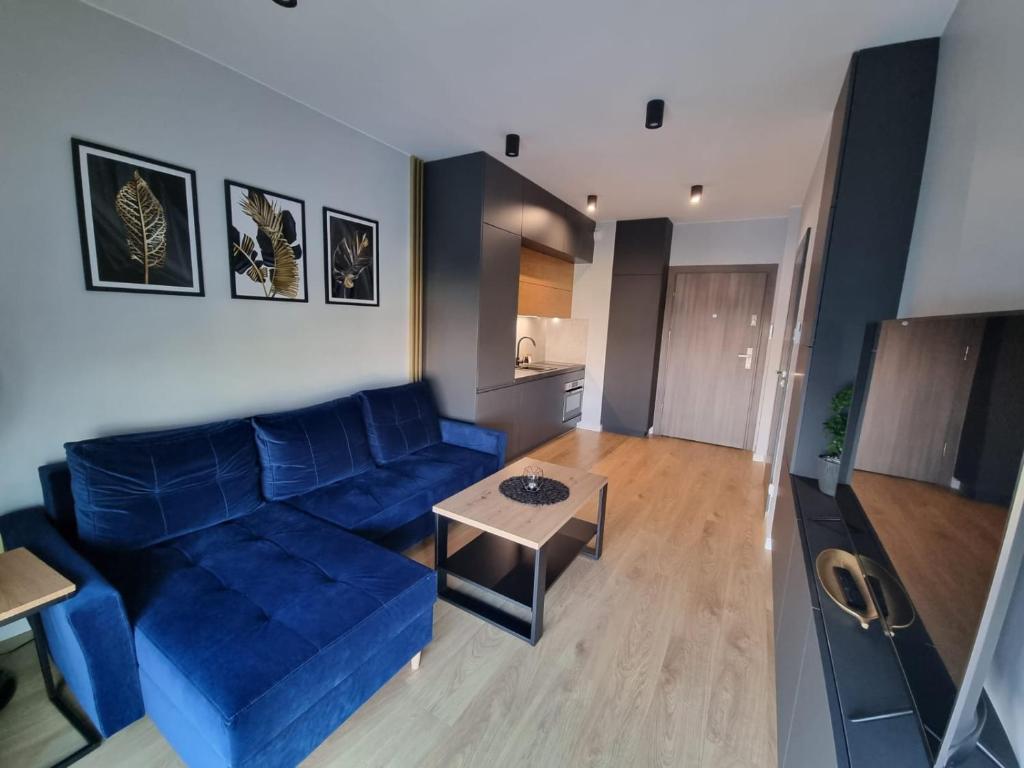 een woonkamer met een blauwe bank en een tafel bij GOLD APARTMENTS Capital Towers in Rzeszów