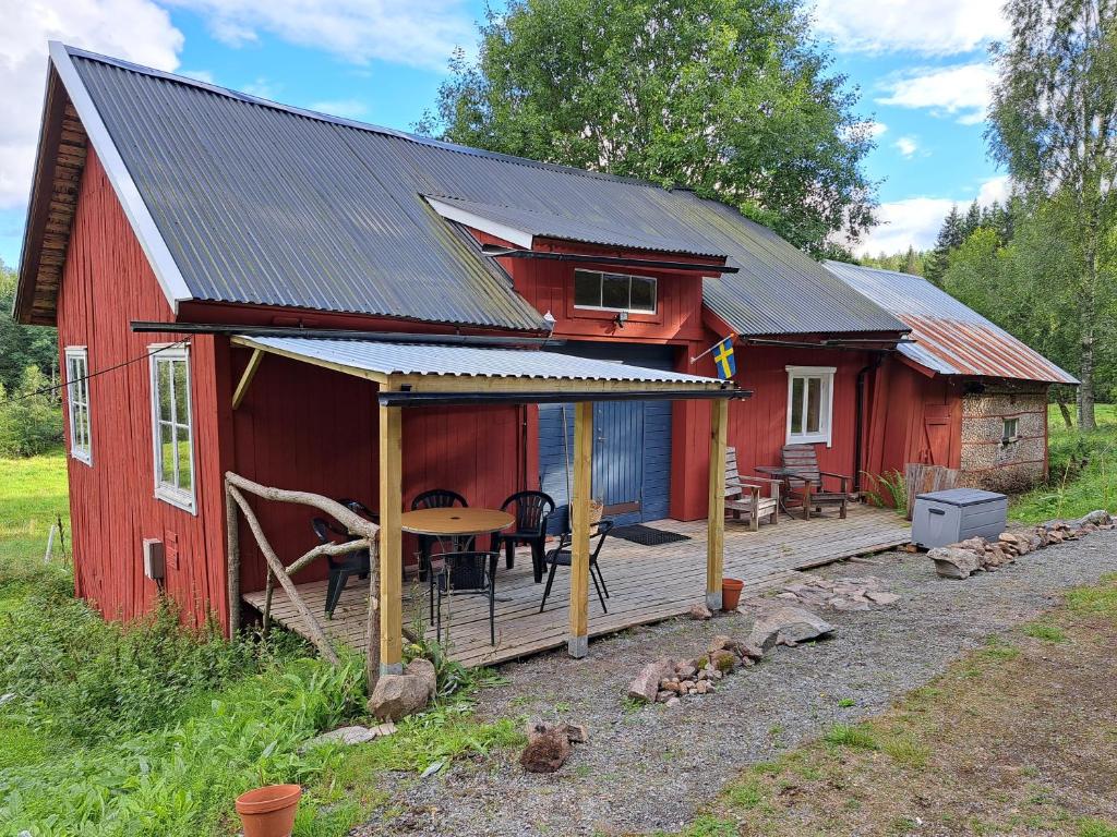a red cabin with a deck and a table at Guesthouse Nature Trails Sweden 