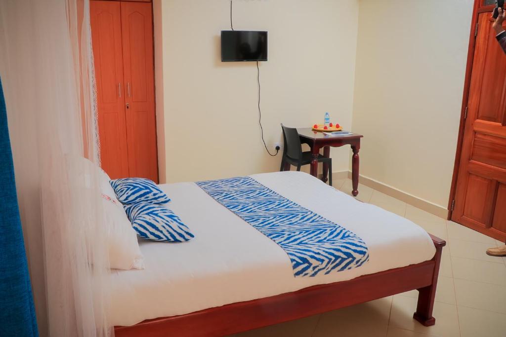 a bedroom with a bed with blue and white sheets at Jatheo Hotel Rwentondo in Mbarara