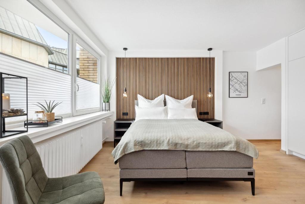 a bedroom with a large bed and a chair at Modernes Studio am Bremer Dom mit Balkon in Bremen