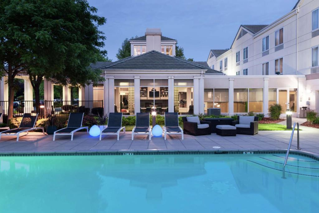 a swimming pool with chairs and a building at Hilton Garden Inn Sacramento/South Natomas in Sacramento