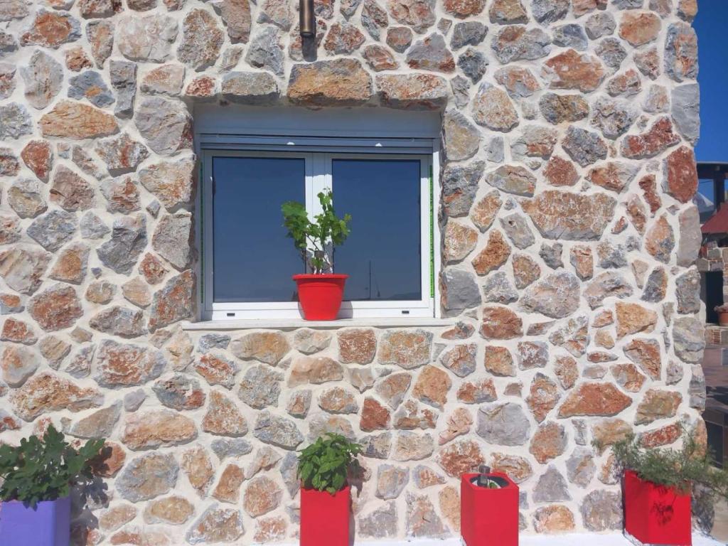 a stone building with a window with two potted plants at Anemomylos House in Kámpos