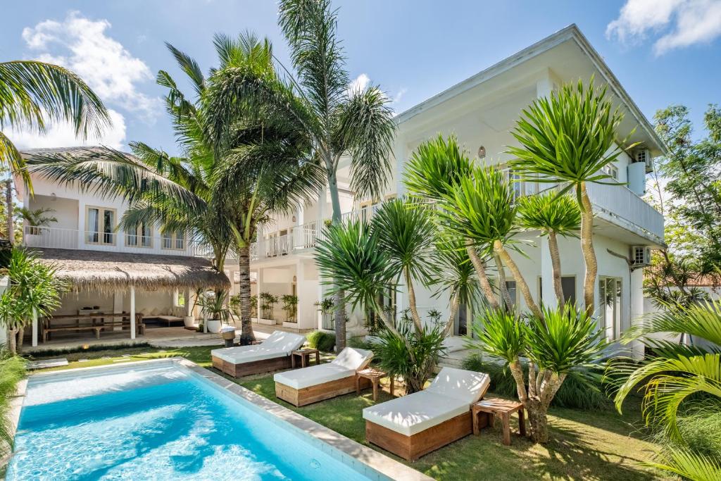 an exterior view of a house with a swimming pool and palm trees at The Warm Sun - Bingin in Uluwatu