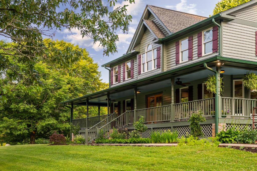 una vecchia casa con portico e prato di The Inn At Amaris Farms a Weaverville