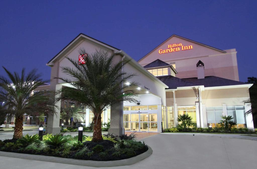 ein Gebäude mit einer Palme davor in der Unterkunft Hilton Garden Inn Covington/Mandeville in Covington