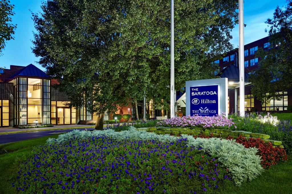 a sign in front of a building with flowers at The Saratoga Hilton in Saratoga Springs